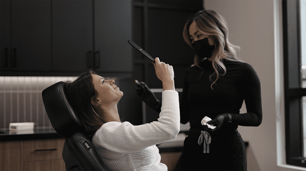 woman looking at her face after receiving botox, lip filler, moxi laser, sculptra and skin care treatment facials in London, Ontario
